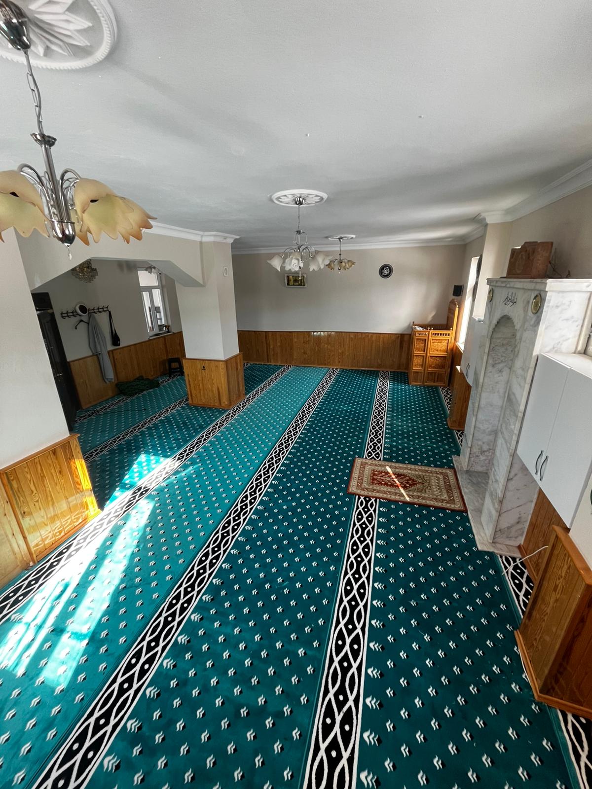 İbadet alanında düzenli saf desenleri bulunan yeşil cami halısı